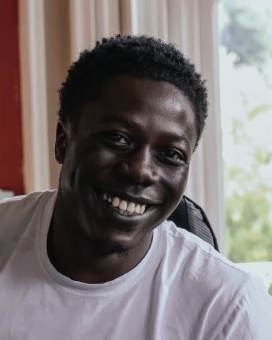 Shina, smiling, in a white T-shirt